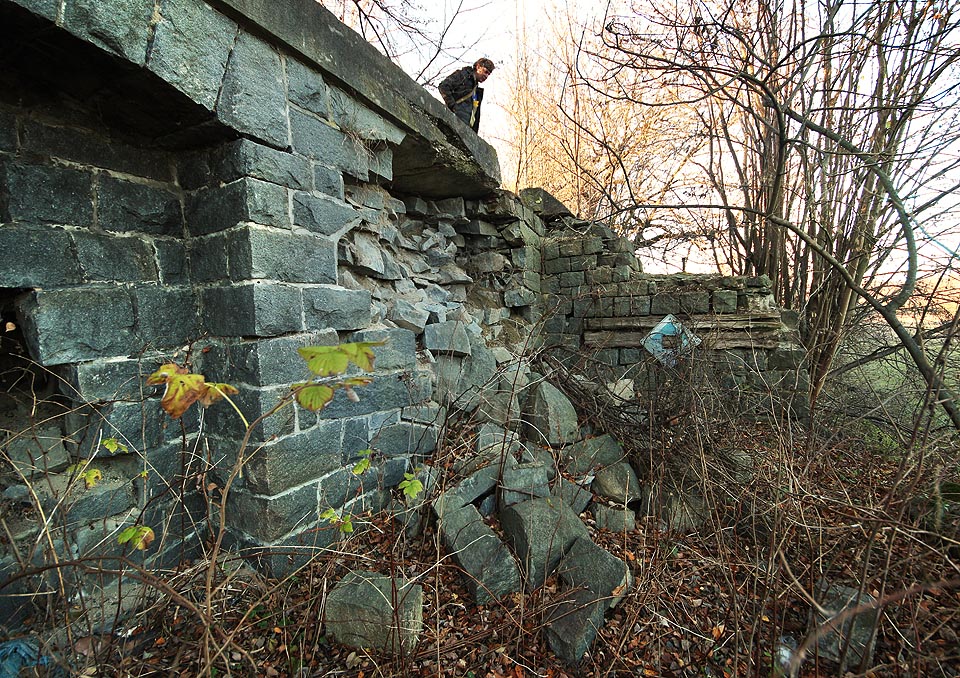 Těsně před koncovým zarážedlem zrušené vlečky se část kamenné zdi sesunula a splynula s přírodou.