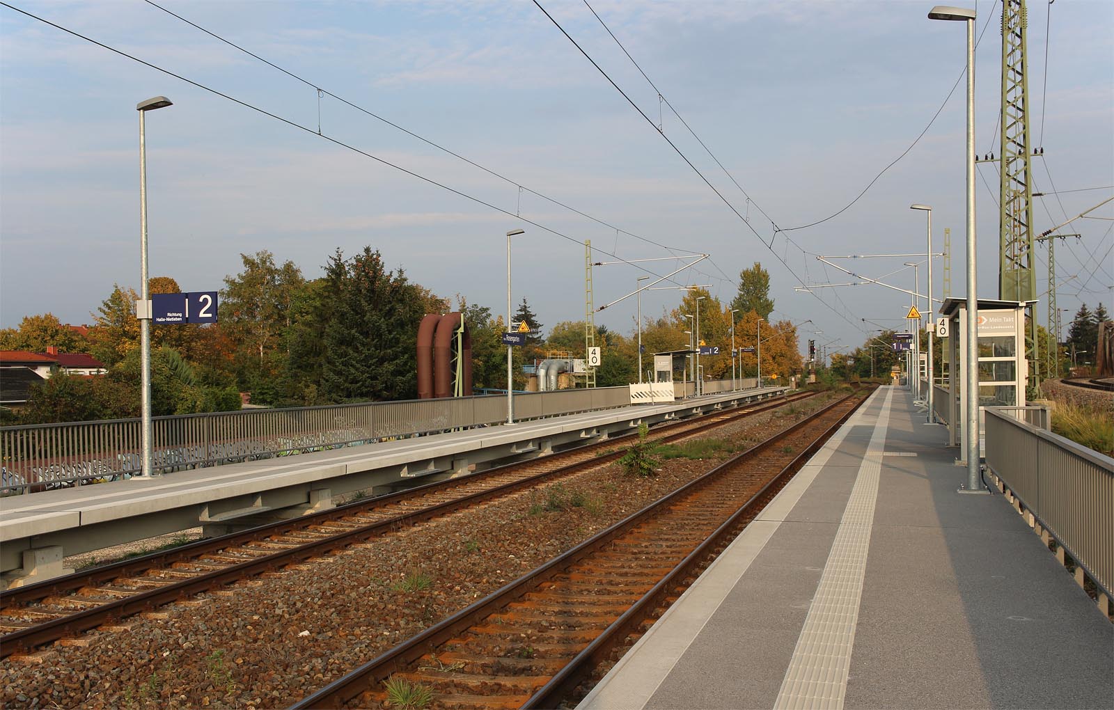 Pohled na moderní zastávku Halle Rosengarten v původní poloze, mírně zvýšenou oproti trati z roku 1865. Zcela vpravo je vidět spojovací kolej ke stanici Ammendorf ležící jižně od Halle.