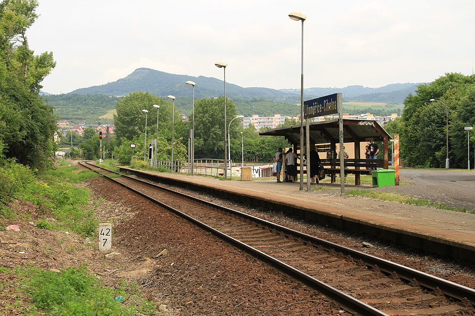 Pohled na zastávku Litoměřice Cihelna od jihu v pozadí s vjezdovým návěstidlem L do stanice Litoměřice horní nádraží a vrcholy Kamýk (455 m) a Hradiště (545 m).