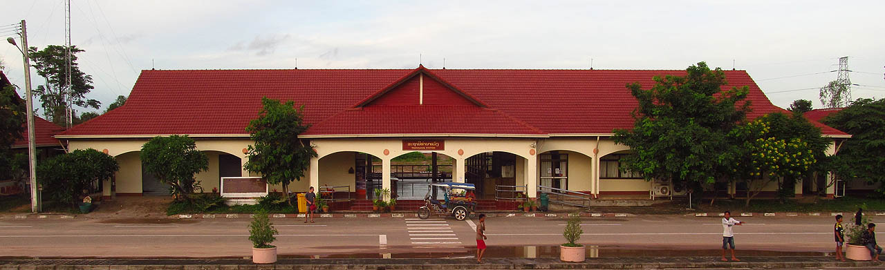 Výpravní budova stanice Thanaleng nedaleko laoského hlavního města Vientiane. Před budovou stojí nezbytná trojkolka zvaná tuk-tuk, bez níž si dopravu v metropoli ani nelze představit.