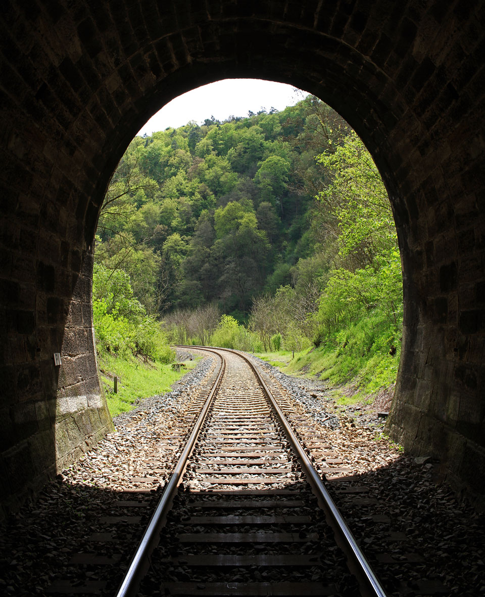 Pohled zpět ke Křivoklátu z jižního portálu tunelu. zatímco na vnějším úseku trati jsou již pražce betonové, v tunelu zůstaly klasické dřevěné, napuštěné karbolem.