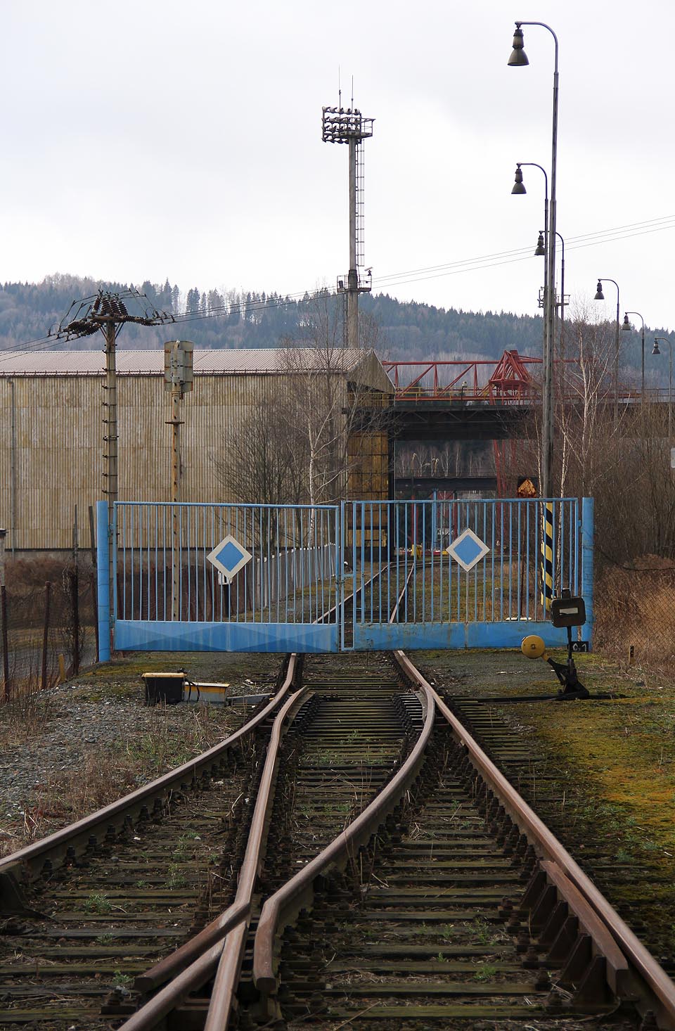Pohled přes bránu do areálu společnosti Vítkovice Hard. Vlevo dole odbočení odvratné koleje.